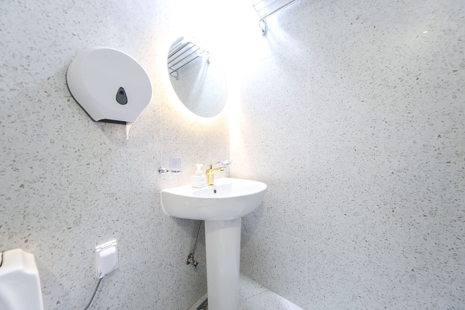 Un baño con lavamanos blanco, un espejo y un secador de manos.