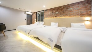Ein Hotelzimmer mit zwei Betten, einer Wand aus Ziegelsteinen, Holzboden und modernem Design.