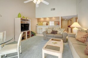 A living room with a sofa, a coffee table, a TV, and a bookshelf.