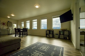 A spacious living area with a dining table, a sofa, and a large window offering a view of the mountains.