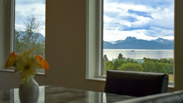 Ein Zimmer mit Blick auf einen See und Berge durch große Fenster.