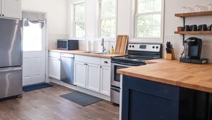 Une cuisine moderne dotée d’appareils électroménagers en acier inoxydable, de meubles blancs et d’un plan de travail en bois.