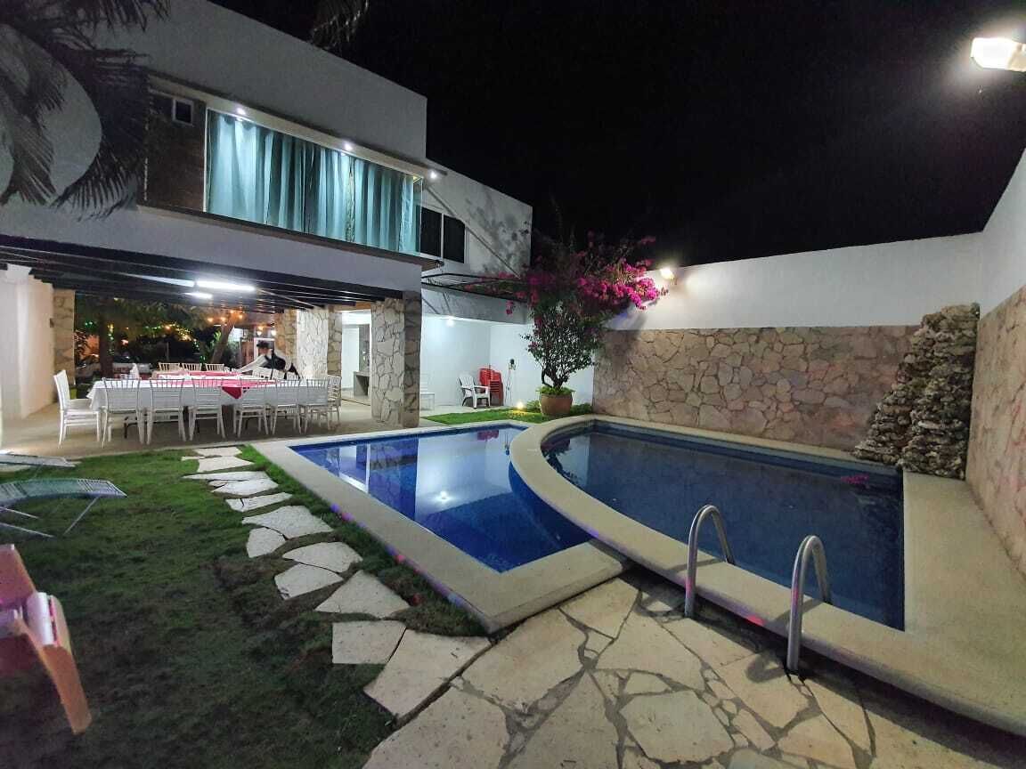 Un área de piscina moderna al aire libre con una pared de piedra y una zona de comedor.