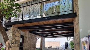 An outdoor dining area with a stone wall, metal railing, and a covered seating area. - Hotel Garden Suites Tonlá (Tonalá)