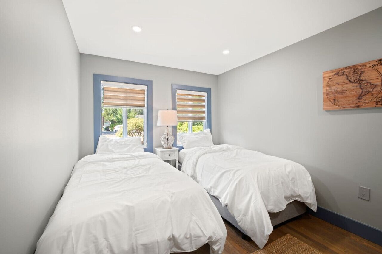 A bedroom with two beds, a nightstand, and a lamp.