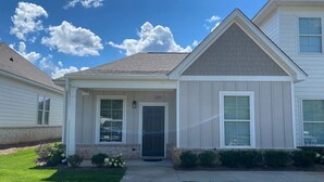 A two-story house with a front porch, a garage, and a well-maintained lawn. - Auburn Gameday Townhome (Opelika)
