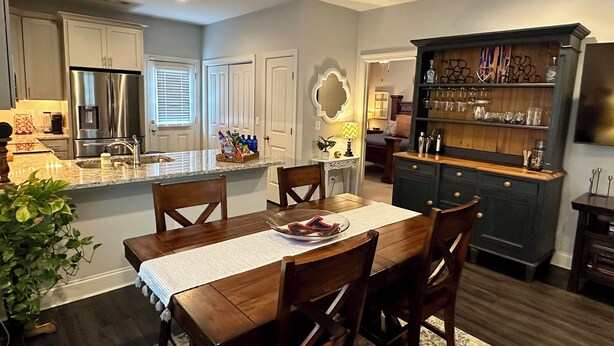 A modern kitchen with a central island, built-in appliances, and a bar area with shelves. - Auburn Gameday Townhome (Opelika)