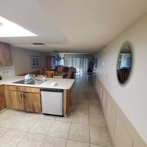 Eine geräumige Küche mit Geschirrspüler, ein Essbereich mit Stühlen und ein großer Spiegel an der Wand.