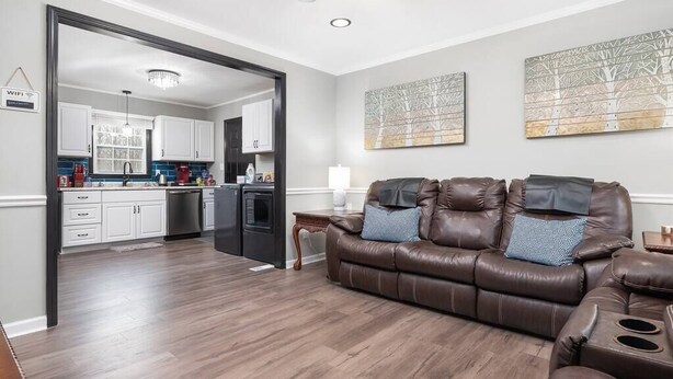 A modern living room with a brown leather sofa, a dining area with white cabinets, and artwork on the walls. - "Crowder's Cottage" — Cozy retreat near Kings Mountain & Gastonia, NC (Gastonia)
