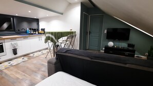 Et moderne køkken med spiseplads, sofa og fjernsyn.