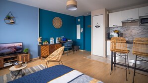 Uma sala de estar moderna com TV, sofá e área de jantar com cadeiras.