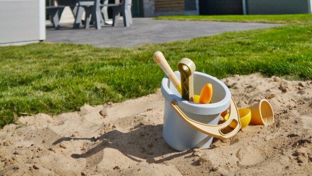 Een modern huis met een schuin dak en een terras met tuinmeubilair.