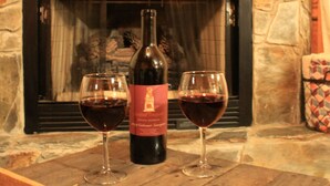 A fireplace with a stone surround, a television mounted above it, and two glasses of red wine on a wooden table in front. - Twin Fox Cabin Peaceful Blue Ridge/Ellijay Retreat (Cherry Log)