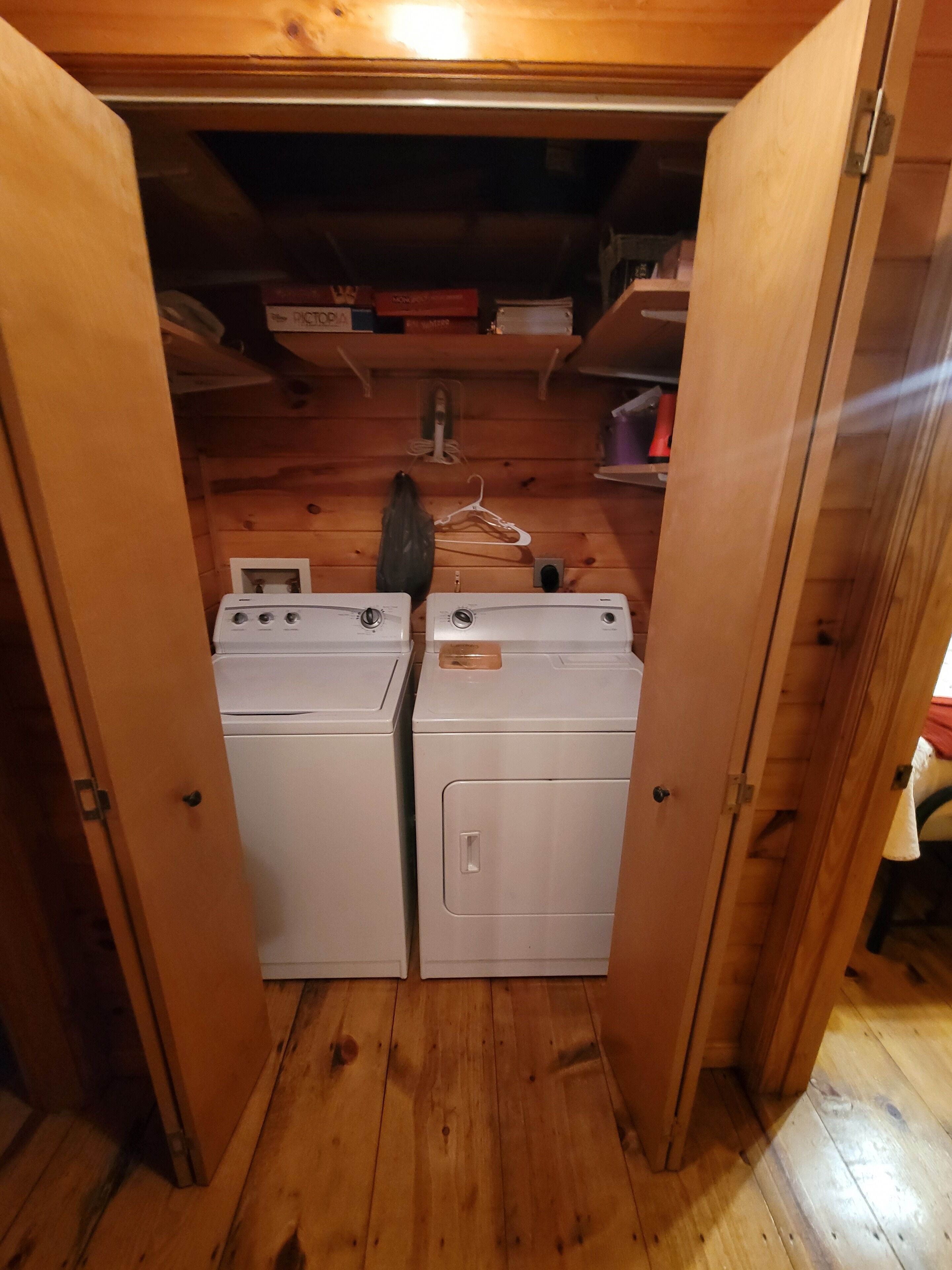 Een wasserette met twee gestapelde wasmachines, houten vloeren en een houten plafond.