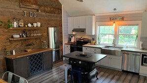 Une cuisine moderne avec des meubles blancs, une cuisinière noire et un îlot central en bois.