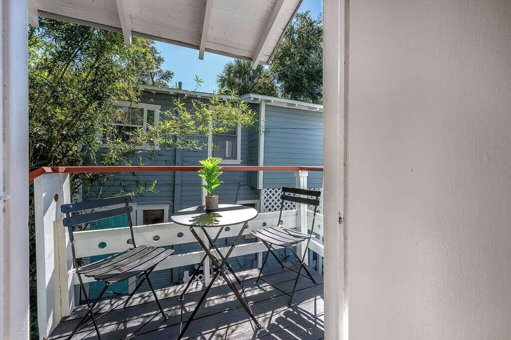 A covered patio with a table and chairs, a potted plant, and a view of a house.