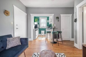 Una sala de estar con un sofá, una mesa de centro y un comedor con una cocina al fondo.