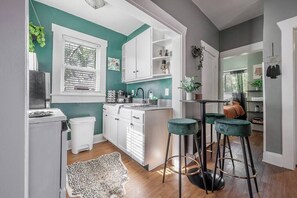 Una cocina moderna con armarios blancos, una isla central y taburetes de bar.