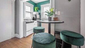 Une cuisine compacte avec un coin repas, des appareils électroménagers blancs et des touches de couleur verte.