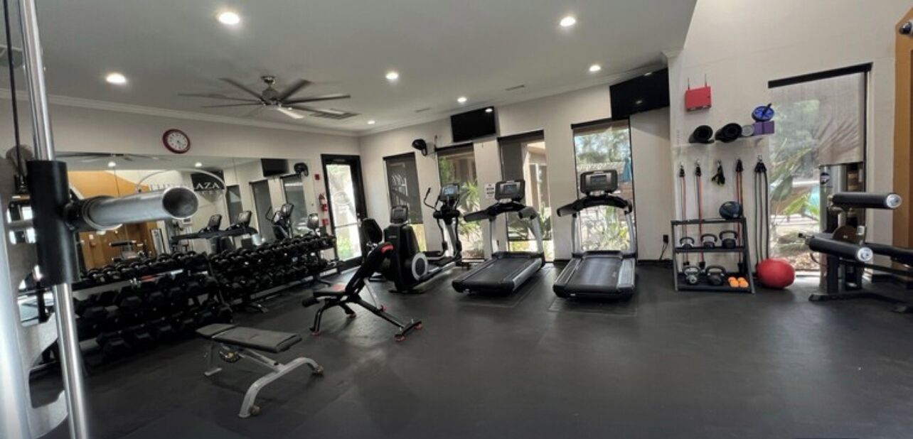 A gym with treadmills, weights, and exercise equipment.