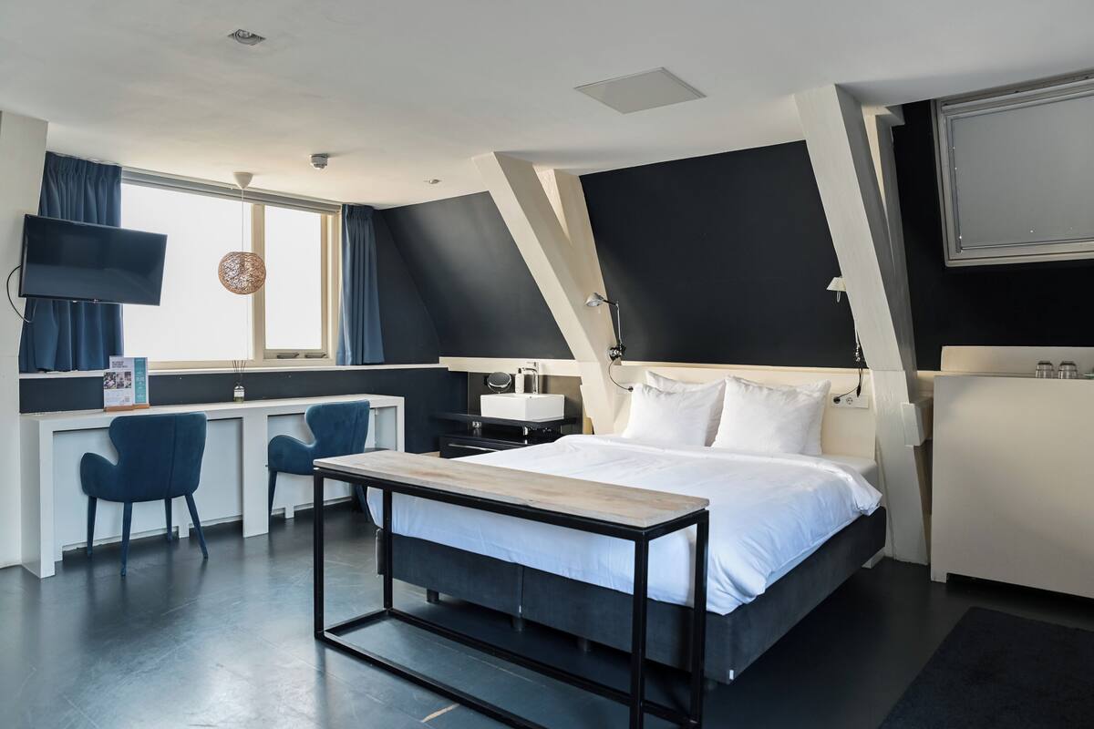 A modern hotel room with a bed, desk, and seating area.