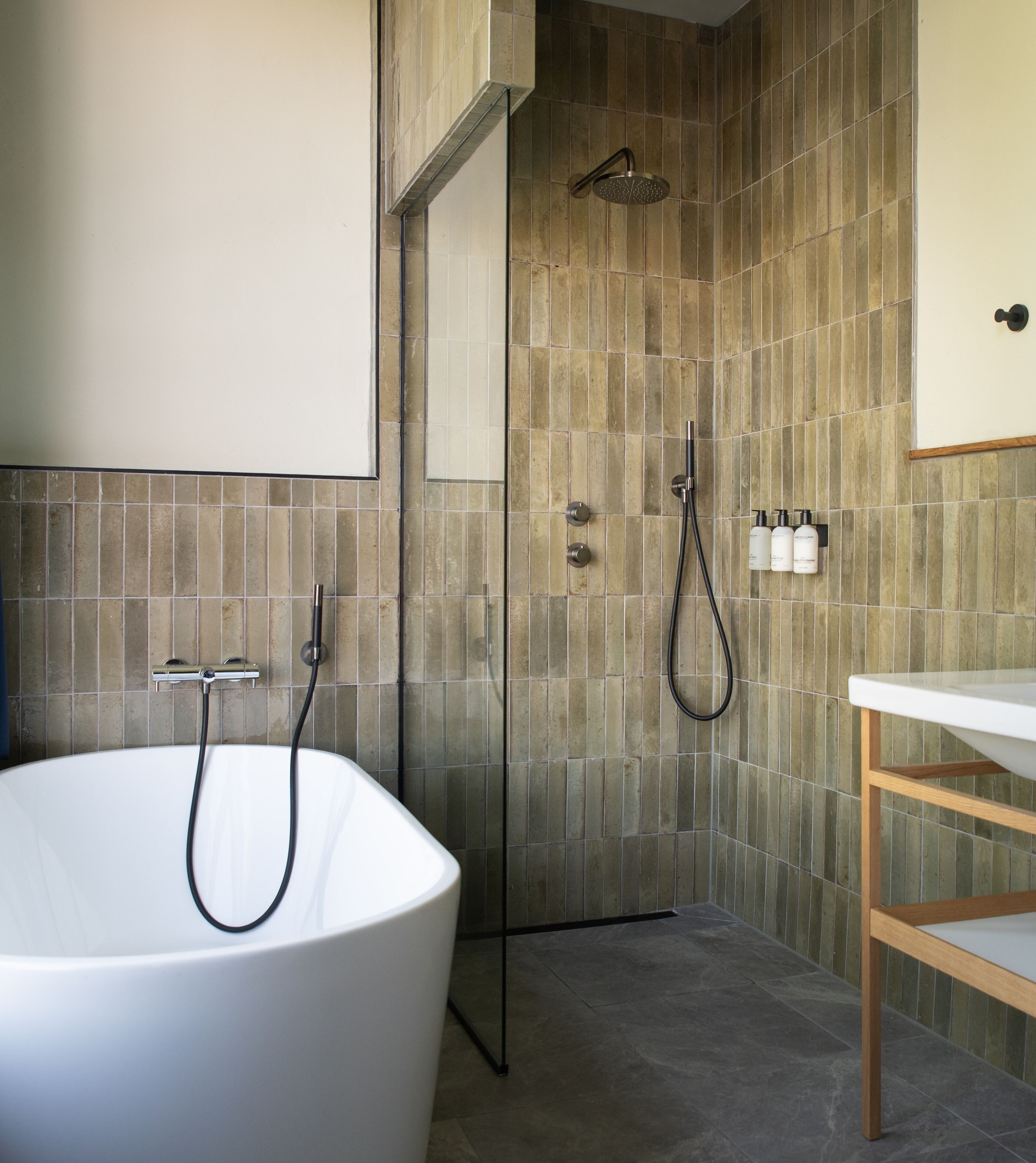 Un baño moderno con una bañera independiente, ducha con mampara de vidrio y tocador de madera.