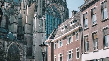 A historic building with intricate architecture, a street with bicycles, and a café with outdoor seating.