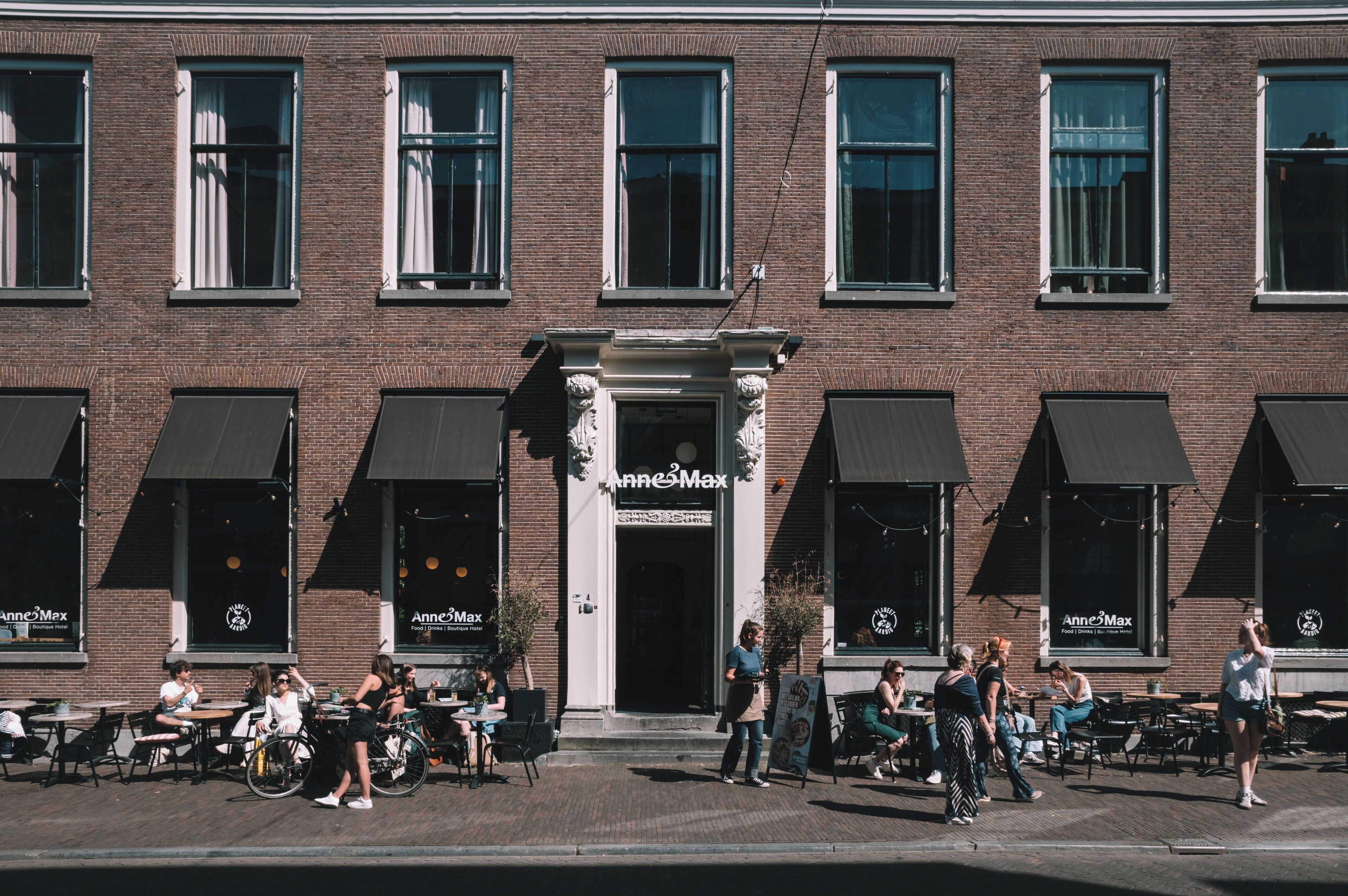 A brick building with a central entrance, outdoor seating area, and multiple windows.