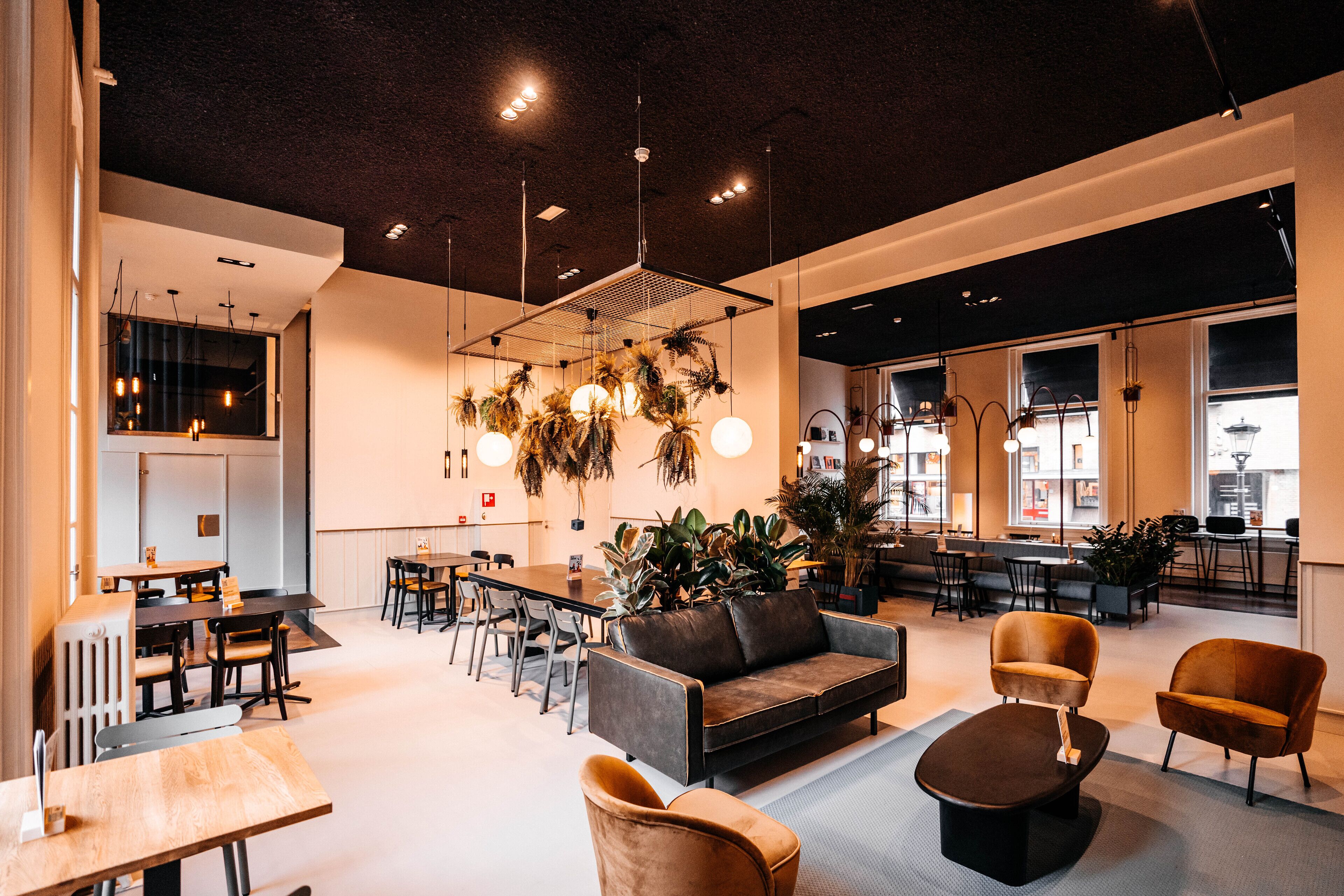 Un interior modern amb zona de menjador, sofàs i una planta gran.