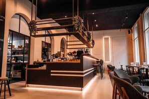 A modern restaurant with a central bar area, seating arrangements, and a kitchen in the background. - Anne&Max Boutique Hotel (Utrecht)