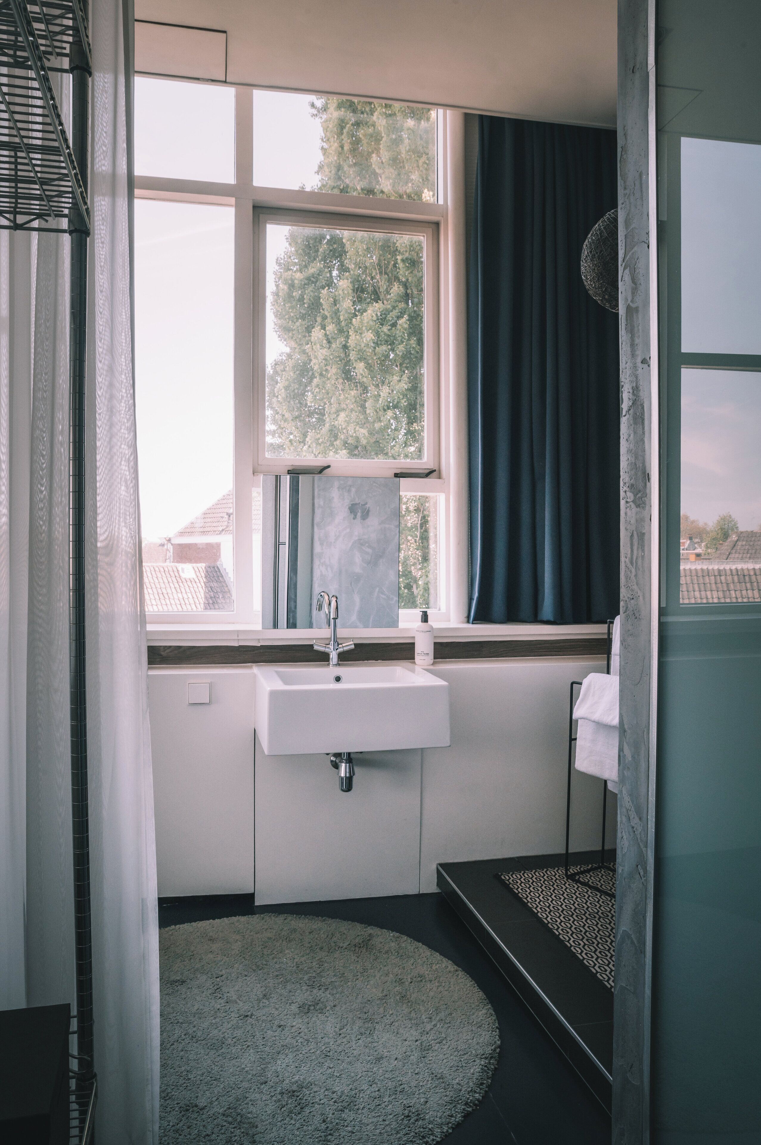 A bathroom with a window, sink, and a towel rack.