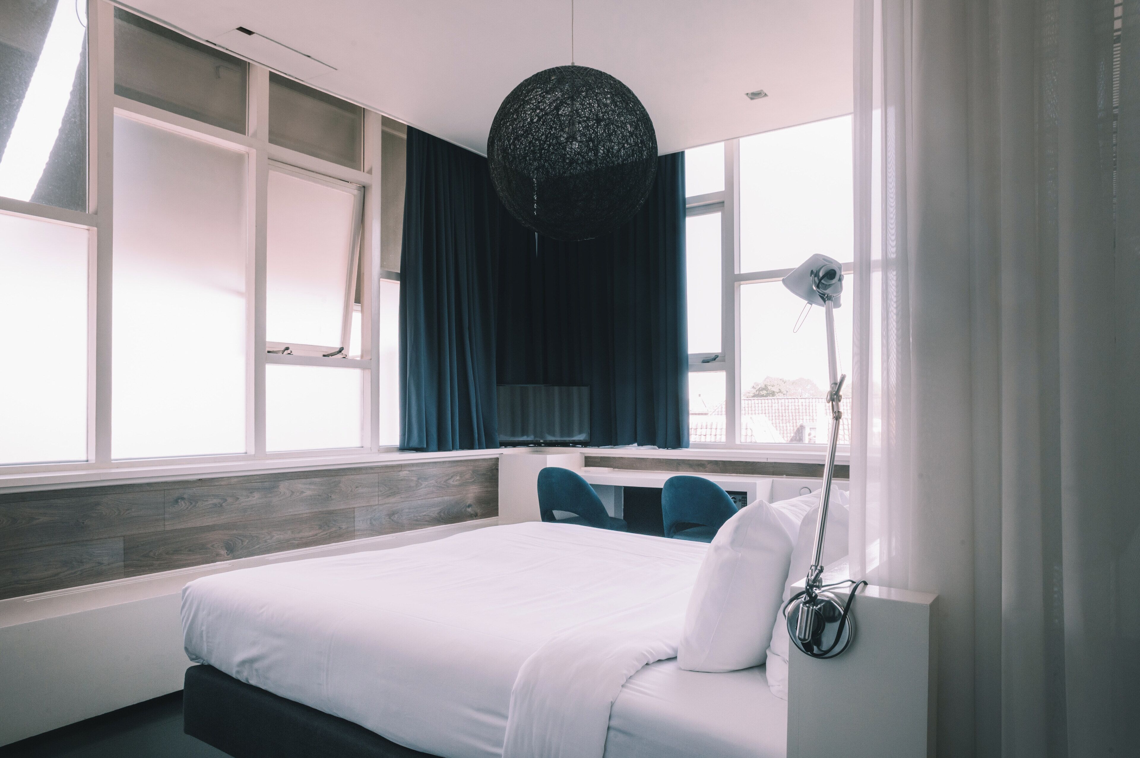 Ein modernes Hotelzimmer mit einem großen Bett, einem Schreibtisch und einem Fenster mit Vorhängen.
