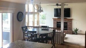 Eine geräumige Küche mit Essbereich, Holzschränken, einer Granitarbeitsplatte und einem Kamin.