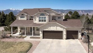 Set against a mountain backdrop, this two-story house offers a scenic view and a covered porch area.
