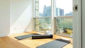 A room with large windows, wooden flooring, and yoga mats. - Luxury Fulton Market Penthouse Amazing City Views (Chicago)