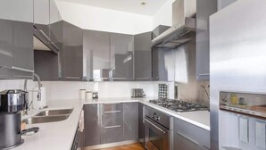 A modern kitchen with stainless steel appliances, a built-in oven, and a gas stove. - Luxury Fulton Market Penthouse Amazing City Views (Chicago)