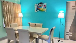A dining area with a table and chairs, a wall-mounted lamp, and a door with a geometric design.