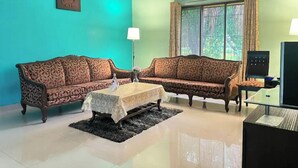 A living room with two patterned sofas, a coffee table, a TV, and a window with curtains.