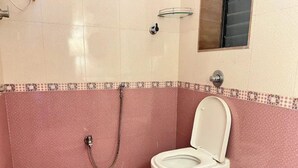 A bathroom with a white toilet, a shower, and a tiled floor.