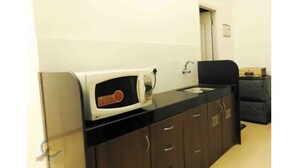 A compact kitchen with a microwave, sink, and dark wooden cabinets.