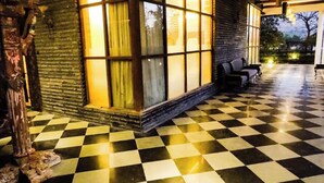 A checkered floor, a large window with curtains, and a stone wall. - LSQ RJ FARMS 3BHK VILLA WITH PRIVATE POOL! (Karjat)