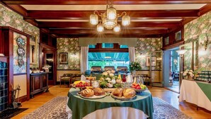 Un coin repas avec une table mise pour le petit-déjeuner, où l’on trouve du pain, des viennoiseries et des fruits.