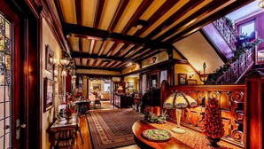 Un intérieur chaleureux, illuminé d’une lumière douce, avec des poutres en bois, un magnifique escalier et une ambiance festive.