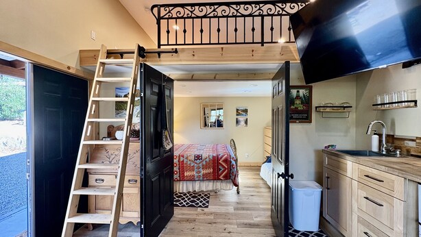 Une pièce compacte avec un lit en mezzanine, une échelle en bois et un coin cuisine.