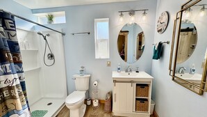 Une salle de bain équipée d’une douche, de toilettes, d’un lavabo et d’un meuble-lavabo.