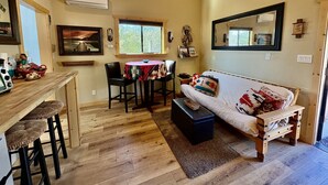 Un salon chaleureux avec un canapé en bois, une table à manger et des chaises, ainsi qu’une grande fenêtre.