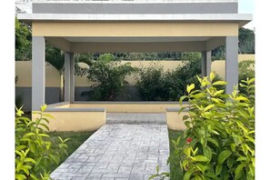 Enjoy a serene outdoor space with a paved walkway leading to a seating area surrounded by lush greenery and a low wall.