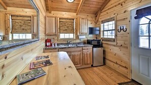 A wooden cabin interior with a kitchen area, including a refrigerator, microwave, and wooden cabinets. - Rustic Ridge Cabins, Charming Retreat (3 Options!) (Dayton)