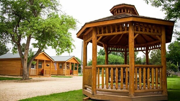 A wooden gazebo with a fenced deck, surrounded by a grassy area and wooden cabins. - Rustic Ridge Cabins, Charming Retreat (3 Options!) (Dayton)