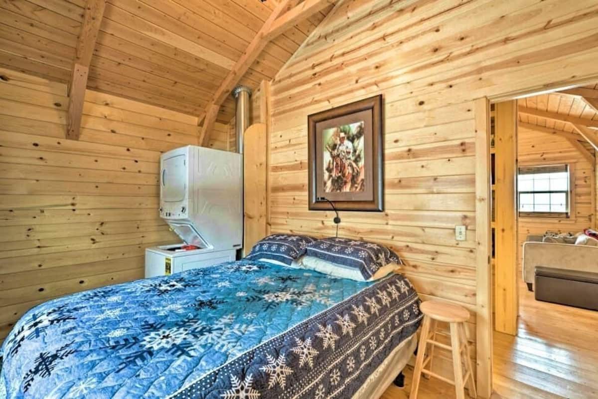 A cozy log cabin bedroom with a bed, a heater, and a framed picture on the wall.